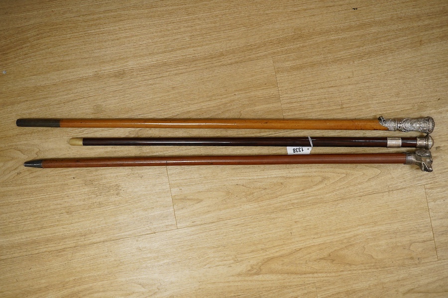 Three 19th century walking sticks, two with silver tops to include a dogs head example, one with unmarked embossed white metal top, largest 97cm in length